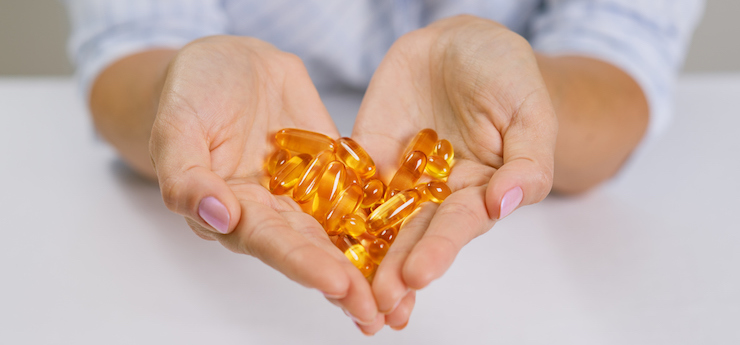 Hands of a woman holding fish oil Omega-3 capsules.