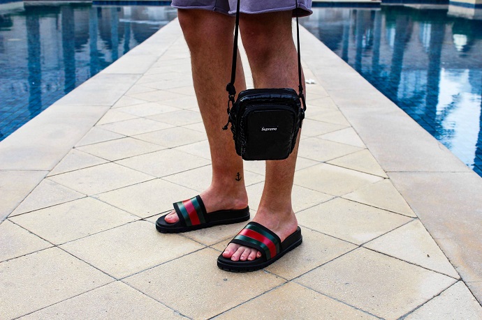 picture of a man walking on tiles beside fountain wearing shorts and sandals