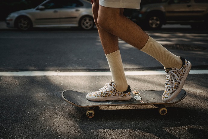 picture of a person on the street riding a skateboard with cool design sneakers and long socks  