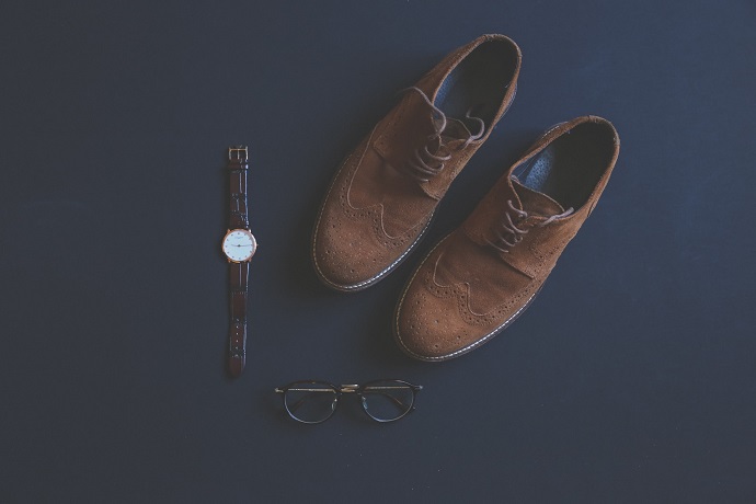 picture of comfortable men's shoes on a blue background beside a watch and pair of glasses