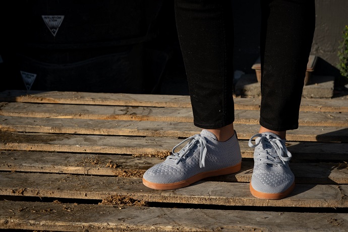 picture of a person standing on a wooden panel, wearing black jeans and blue sneakers