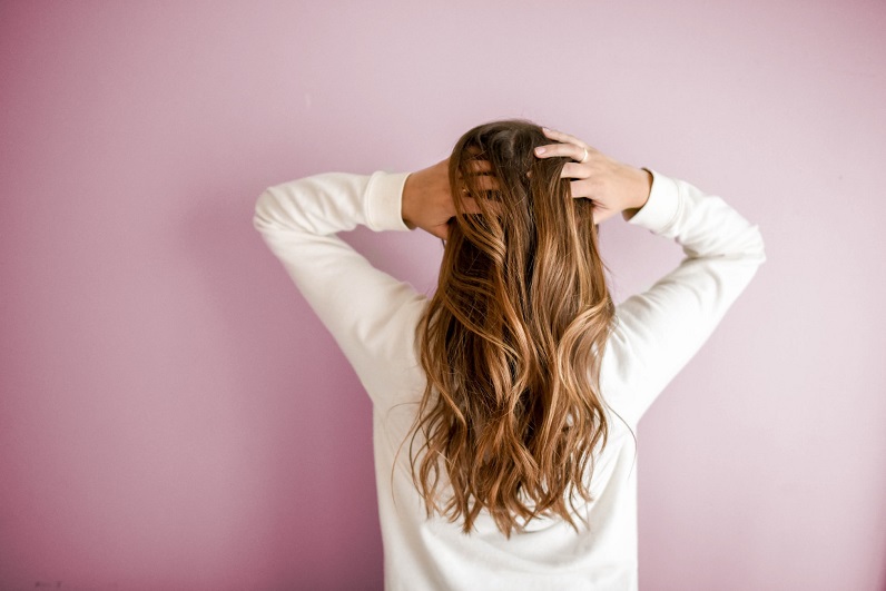 picture of a woman with hands in her hear in front a pink wall 