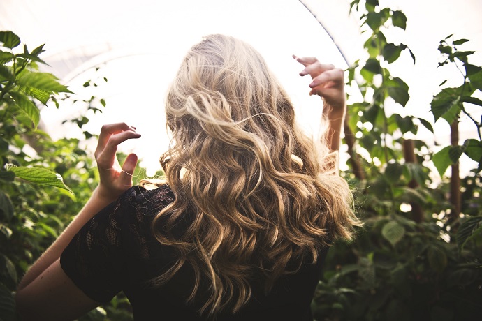 picture of a woman on the sun beside greenery 