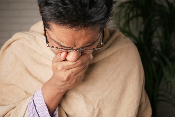 picture of a man with a blanket sneezing in his hand